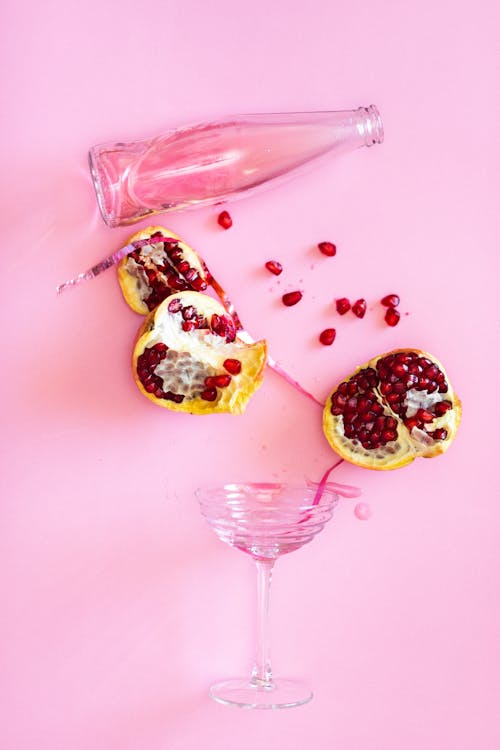 Pomegranate and Glass Bottle on Pink Surface
