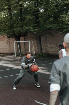 Men playing basketball outdoors on a cement court in a prison yard setting.