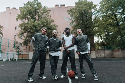 Free Four men in casual uniforms stand on an outdoor basketball court, ready to play. Stock Photo