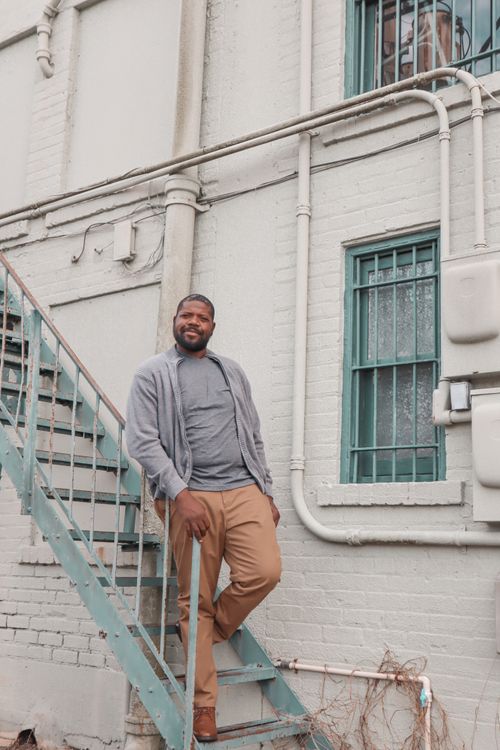 Free Smiling man with facial hair standing on outdoor metal stairs in urban setting. Stock Photo
