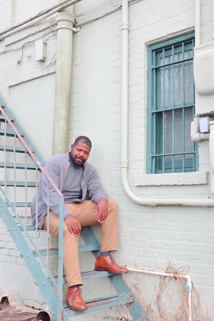 Man Sitting On Stairs Near Building Window