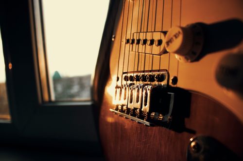 Free Ambient close-up of an electric guitar's bridge illuminated by sunset light through a window. Stock Photo