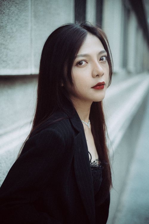 Free Stylish woman with black hair posing against a city wall in an urban setting. Stock Photo