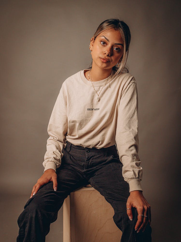 Woman In Beige Long Sleeves Shirt And Black Cargo Pants Sitting On Wood Box