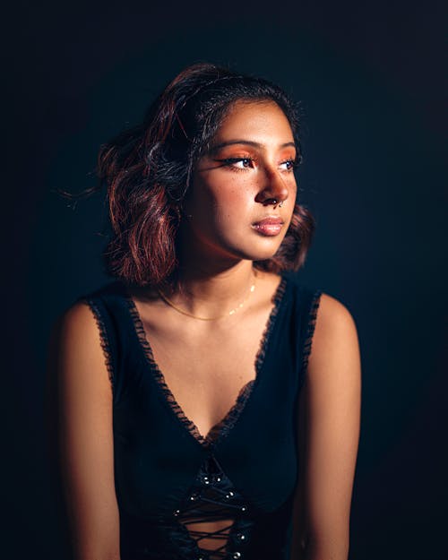 Studio Shot of a Young Woman in a Black Blouse, Sitting and Looking to the Side 