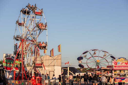 Lively fairground scene with two Ferris wheels, food stalls, and crowd enjoying a sunny day.