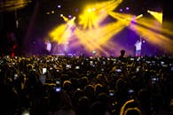 音乐会现场热闹非凡，一大群人在戏剧性的灯光下用手机记录这一刻