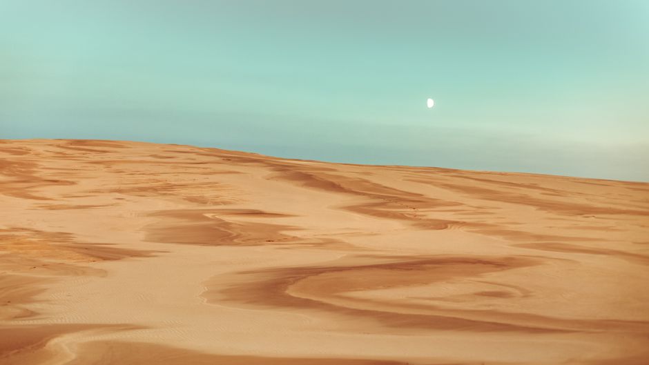A tranquil view of sandy dunes under a dreamy twilight sky in Leba, Poland.