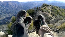 两名徒步旅行者穿着靴子，休息时俯瞰着风景优美的山地景观