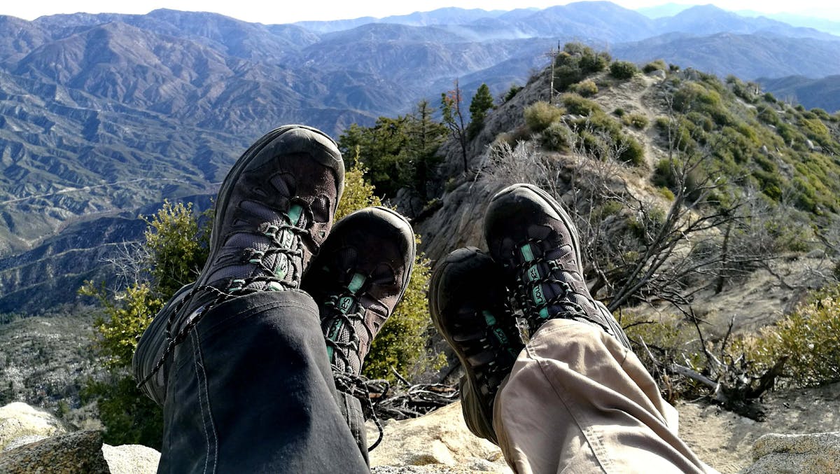 Two hikers wearing sturdy hiking boots on a rocky mountain trail