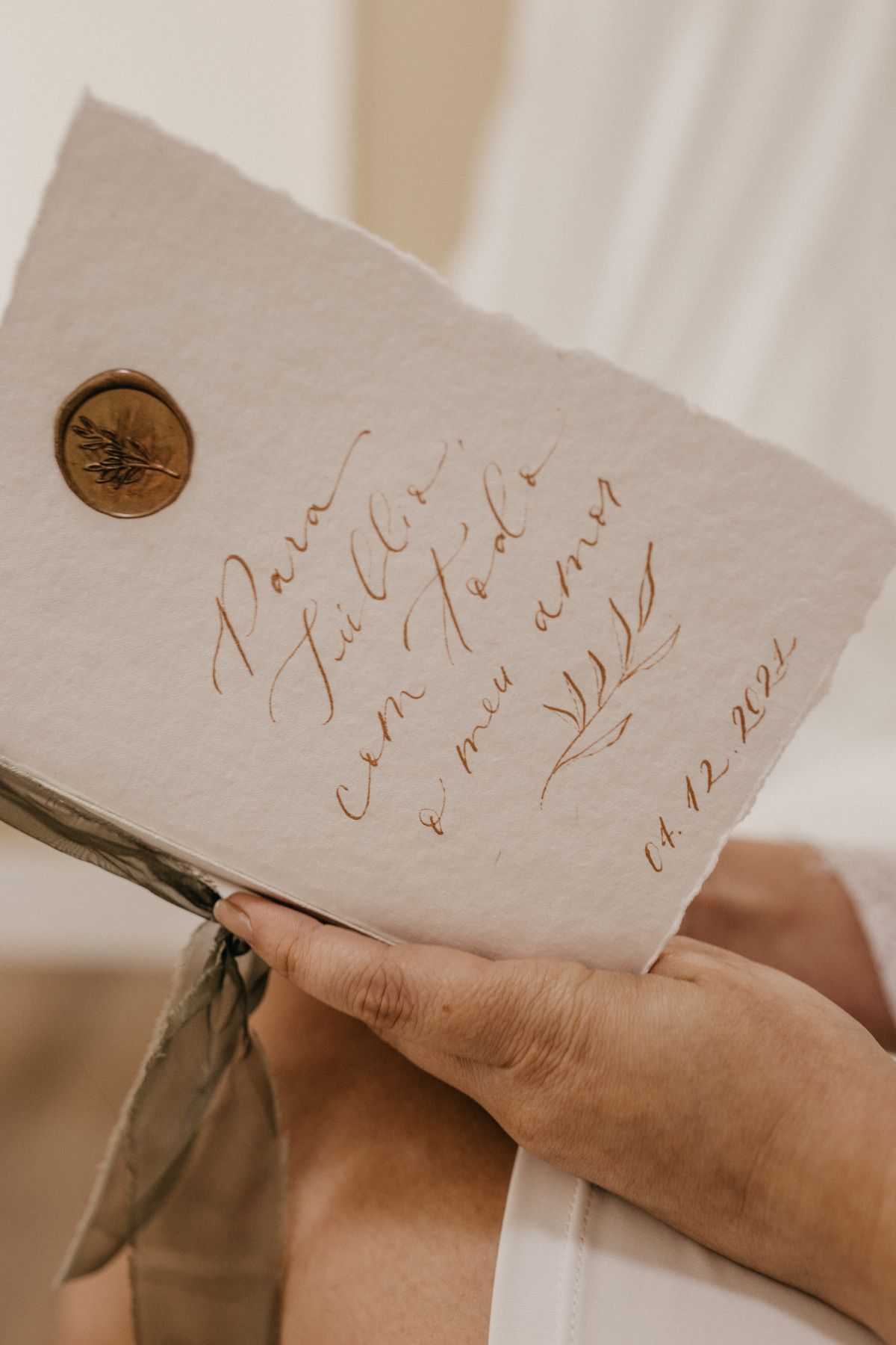 Baby shower invitation ideas with a hand holding a calligraphy card with a wax seal