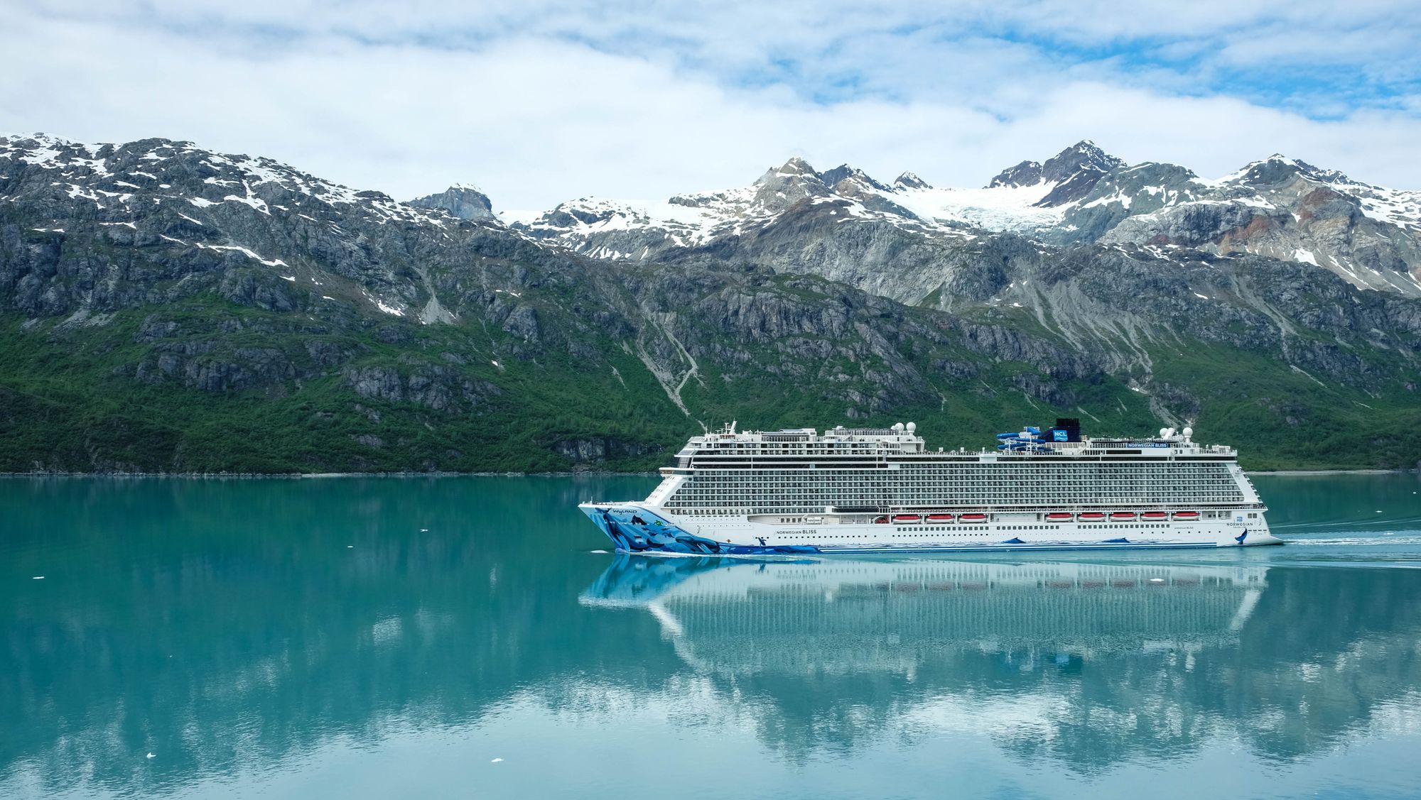 A cruise ship sailing near snow-covered mountains in Alaska