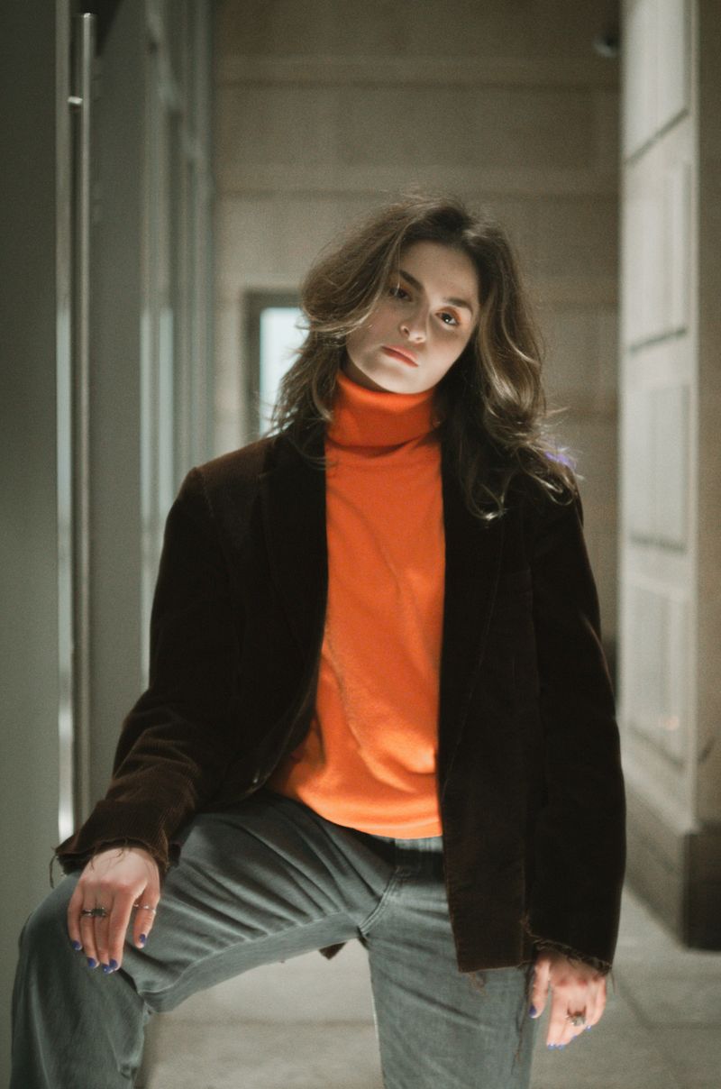 Woman in an orange turtleneck and brown coat