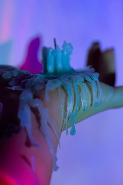 Free Artistic shot of melted candle wax cascading over a hand against a colorful background. Stock Photo