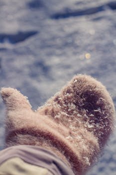 Close-up of wool mittens with snowflakes, capturing winter warmth.