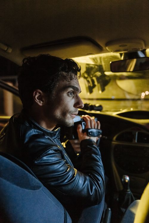 Free Man sitting in a car at night holding a camcorder, capturing hidden footage. Stock Photo