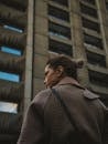 Woman with Tied Hair in Checkered Coat Standing Before Tall Building