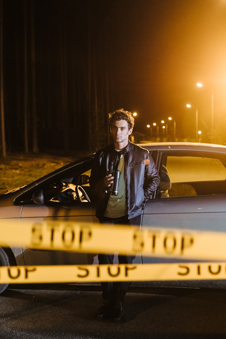 A Man In Black Jacket Standing Near The Car Parked On The Street At Night