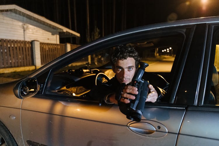 A Man Sitting In The Car While Holding A Video Camera 