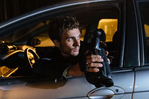 Free Man holding a camcorder in a car at night, looking over shoulder. Stock Photo