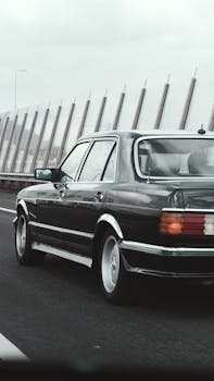 A black vintage luxury car driving on a highway in Amsterdam, showcasing elegance and travel.