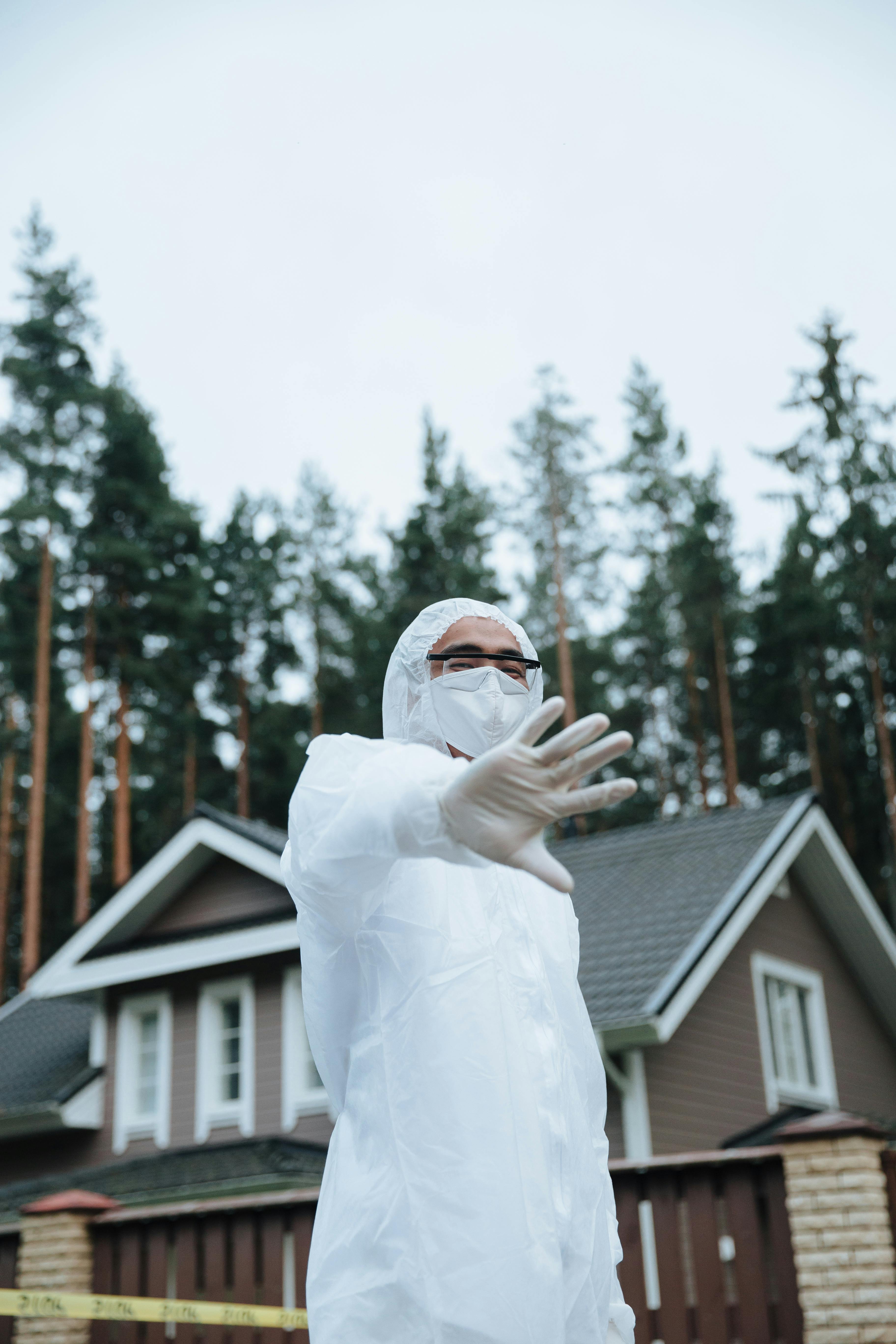 crime scene investigator in a white suit and face mask standing at a crime scene