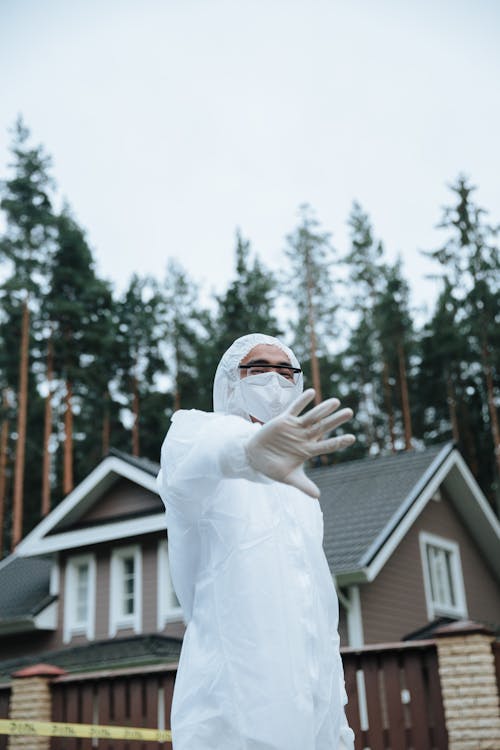 Crime Scene Investigator in a White Suit and Face Mask Standing at a Crime Scene 