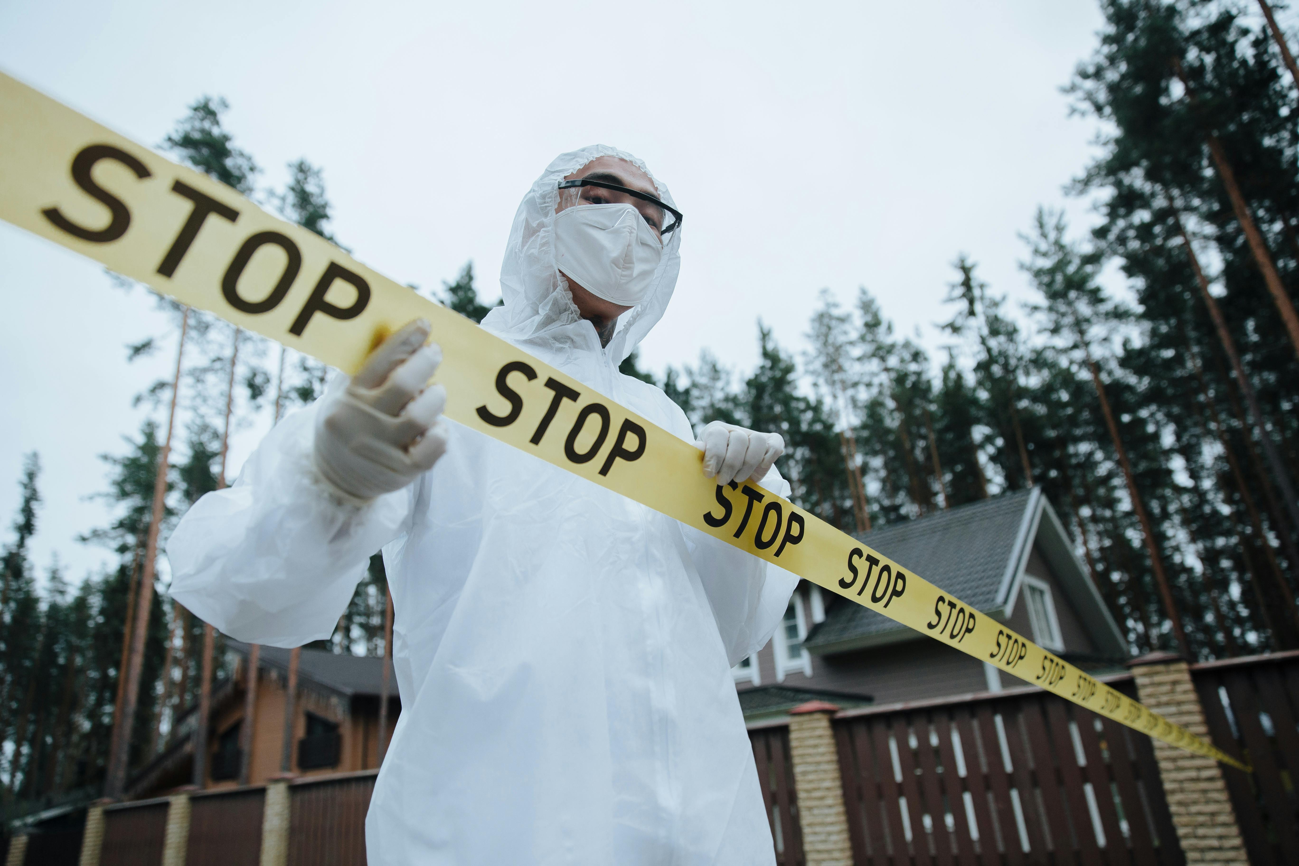 man in a white suit standing behind a crime scene tape