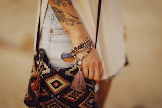 Unrecognizable Female Hand with Tattoos and Bracelet and Figured Shoulder Bag