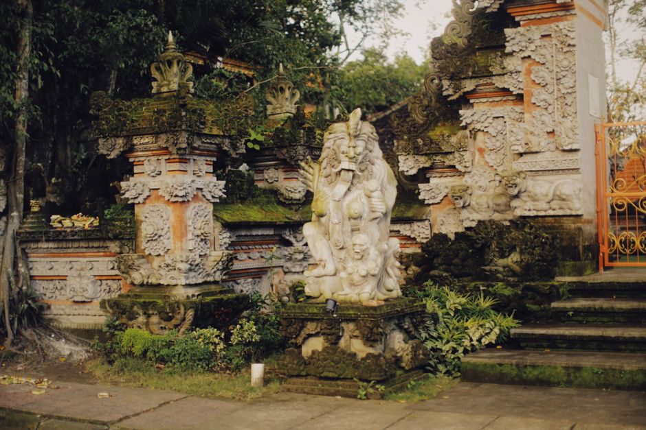 Intricate stone sculptures and ornate architecture at an ancient temple entrance surrounded by lush greenery.