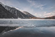 白雪覆盖的山脉环绕着一个冰冻湖泊，景色壮丽