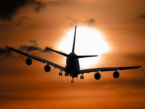 日没時に飛んでいる飛行機の影の画像