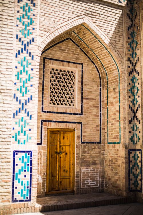 Free Intricate mosaic tiles and wooden door in Gijduvon, Uzbekistan. Stock Photo