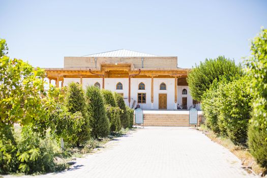 Explore the charming exterior of a traditional Uzbek house in Gijduvon surrounded by greenery.