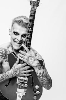 Expressive black & white portrait of a tattooed guitarist with an electric guitar, showcasing rock spirit.