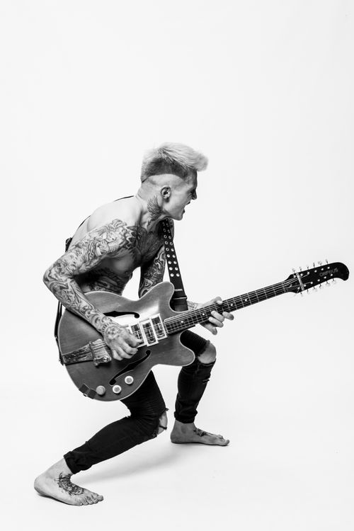 Free Dynamic shot of a tattooed guitarist passionately playing in black and white. Stock Photo