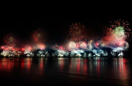 Colorful fireworks reflecting over water in Ras Al Khaimah at night, capturing a festive celebration.