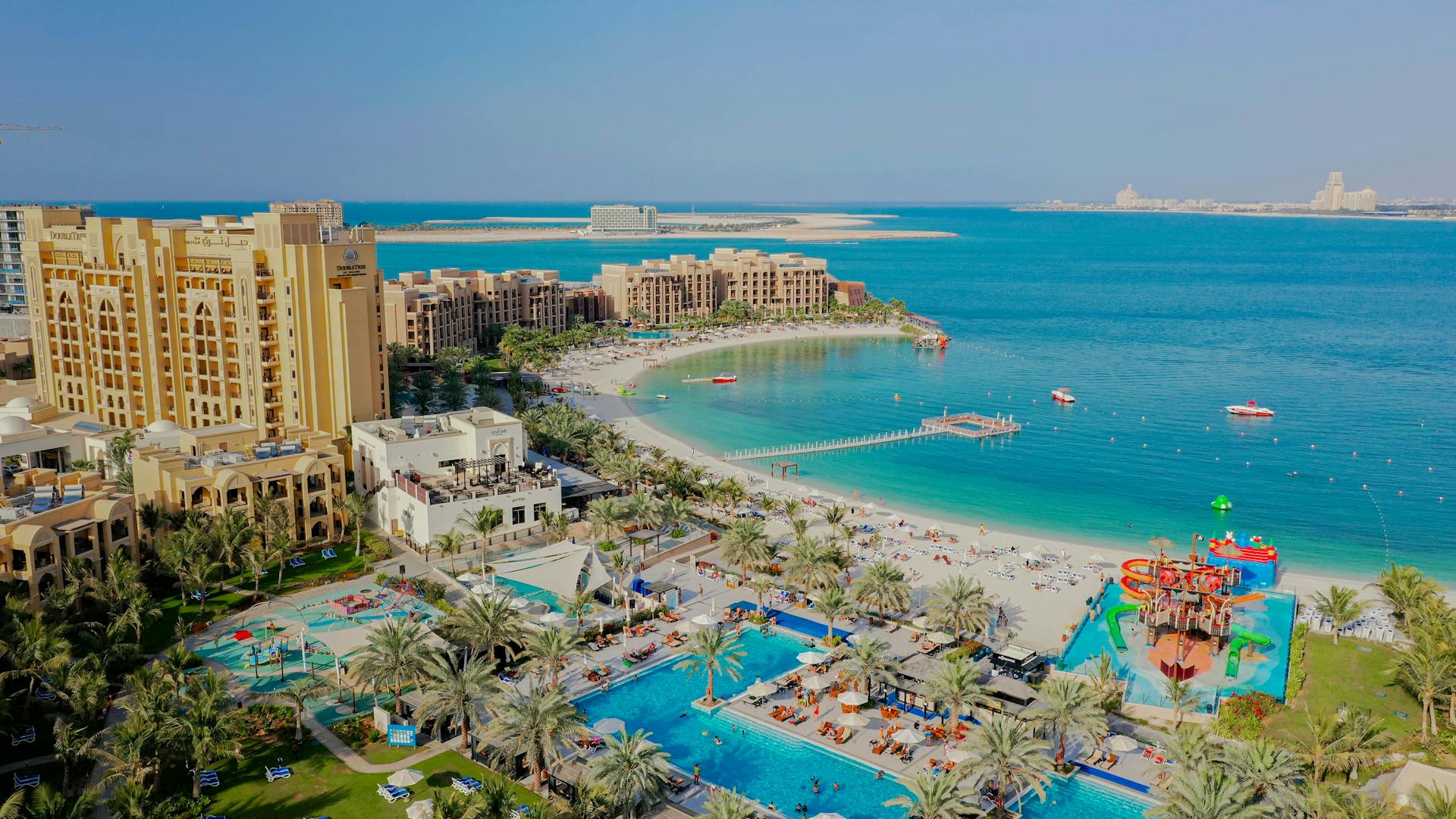 Aerial view of a luxury resort with beach and pool in Ras Al-Khaimah, UAE.