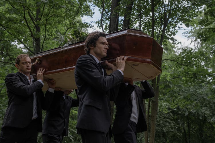 Men In Black Clothes Carrying A Coffin