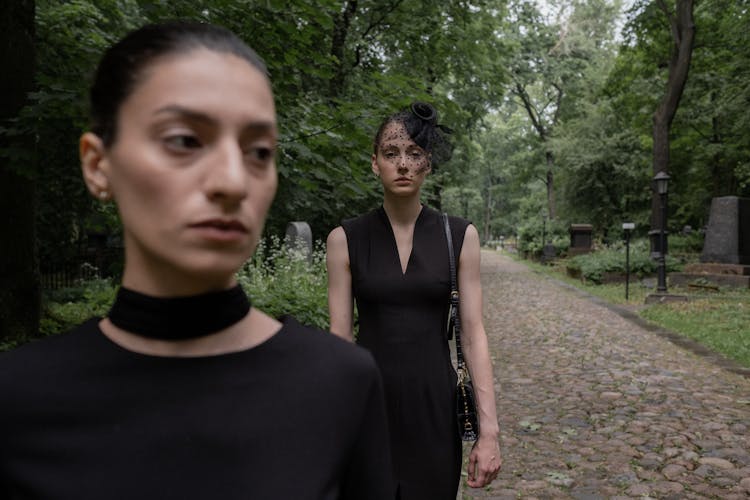 Women In Black Dresses Standing In A Cemetery