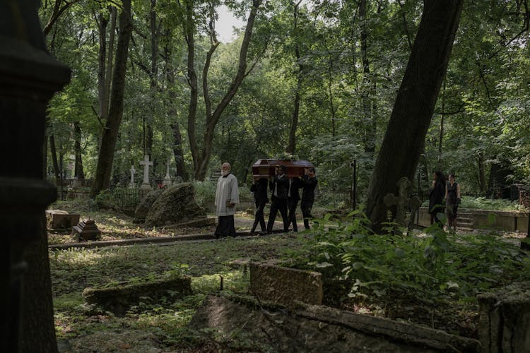 A People Carrying Coffin In Graveyard