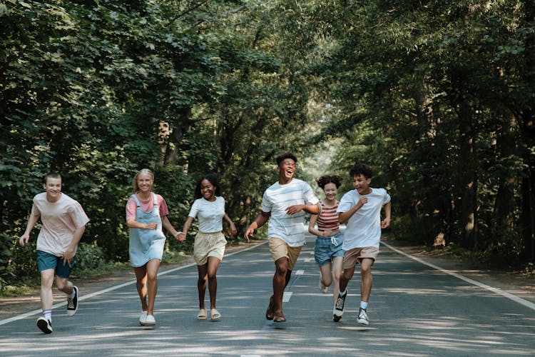 Teenagers Running On Road In Forest