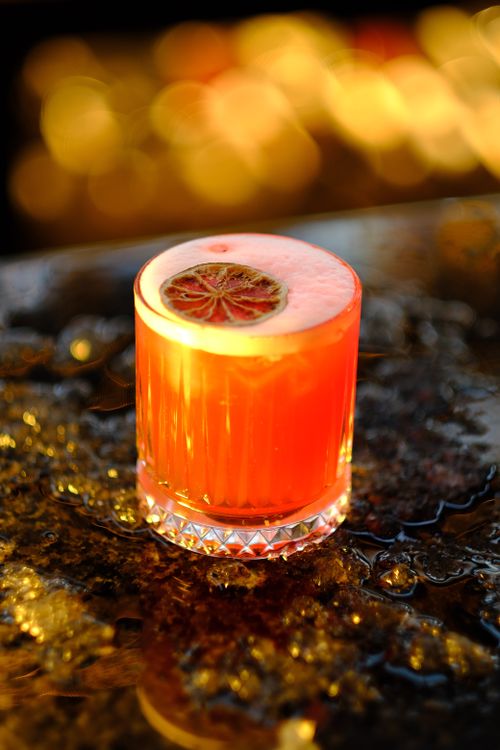 Free Close-up of a bright citrus cocktail with an orange garnish on a textured surface. Stock Photo