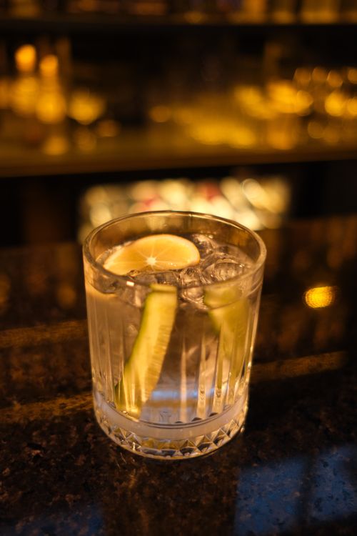 Free Close-up of a cocktail with lemon and cucumber slices on a bar counter with blurred background. Stock Photo