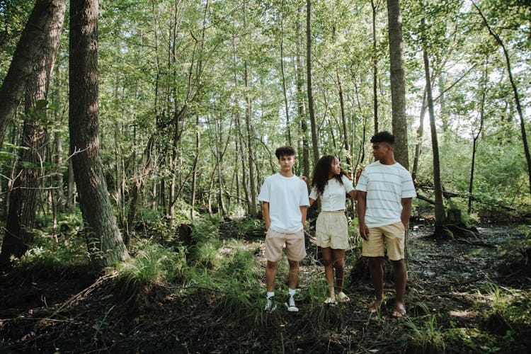 Two Teenage Boys And Girl Standing In Group In Forest