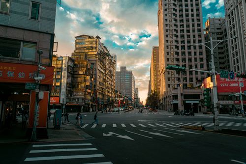 Free Scenic view of a vibrant city intersection at sunset with pedestrians and high-rise buildings. Stock Photo