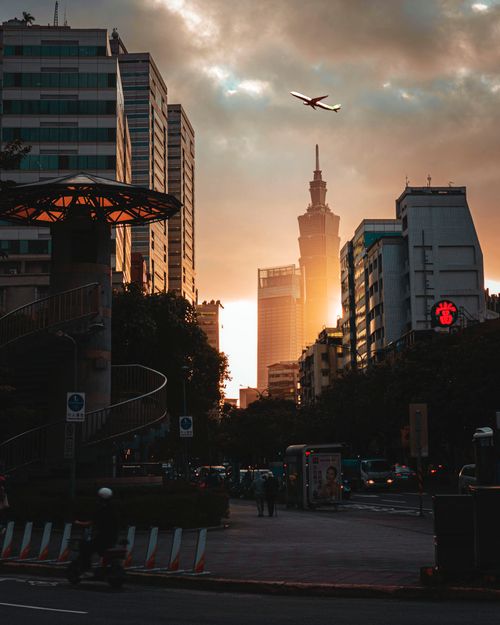 Free Dramatic sunset over Taipei skyline with airplane flying above city buildings. Stock Photo
