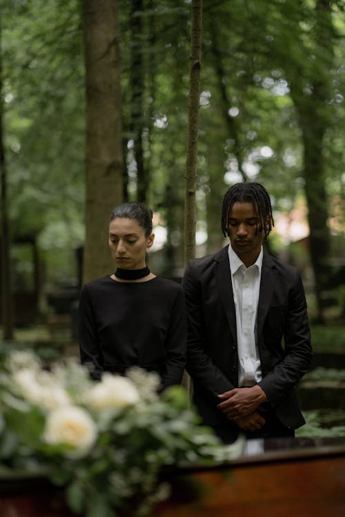 Young Man and Woman Standing near the Coffin at a Funeral 