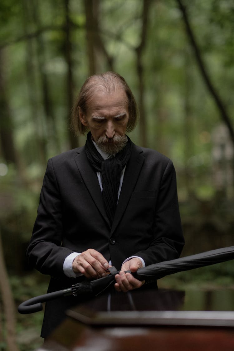 Elderly Man In Black Suit Holding A Black Umbrella 