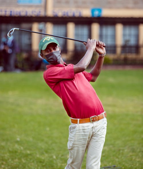 Free A Man in Red Polo Shirt Holding a Golf Club Stock Photo